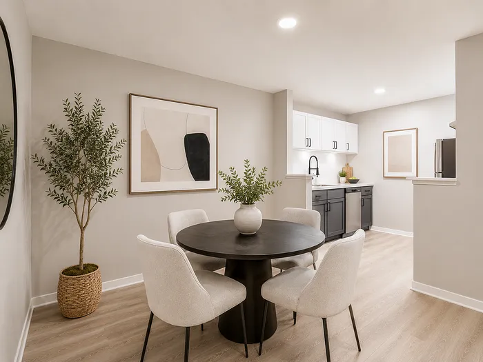 Modern dining area with elegant round table, cozy chairs, and a stylish kitchen featuring sleek cabinetry and stainless steel appliances.