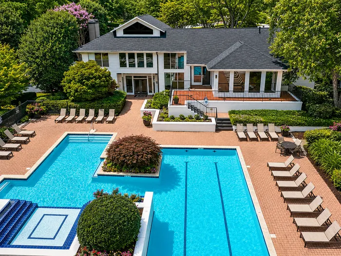 Luxurious poolside escape with elegant lounge chairs and vibrant garden landscape surrounding a charming residential property.
