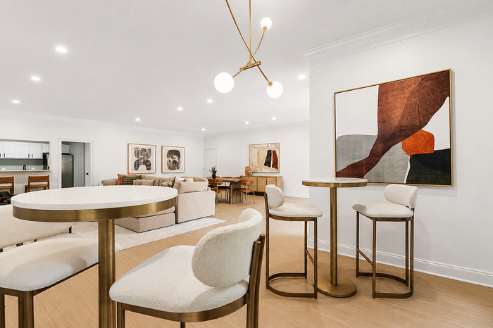 Modern open-concept living space with elegant pendant lighting, stylish bar seating, and chic abstract art decor.