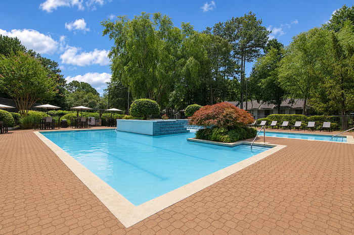 Inviting outdoor pool area with crystal-clear water, surrounded by lush greenery and sun loungers, perfect for relaxation.