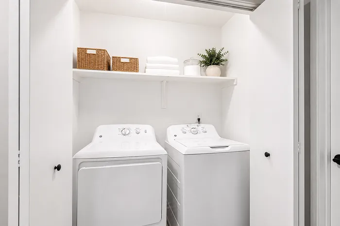 Modern laundry room with sleek washer and dryer, custom shelving, and elegant decor.