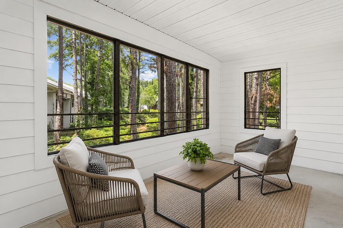 Inviting sunroom with wicker seating, lush forest views, and a serene atmosphere.
