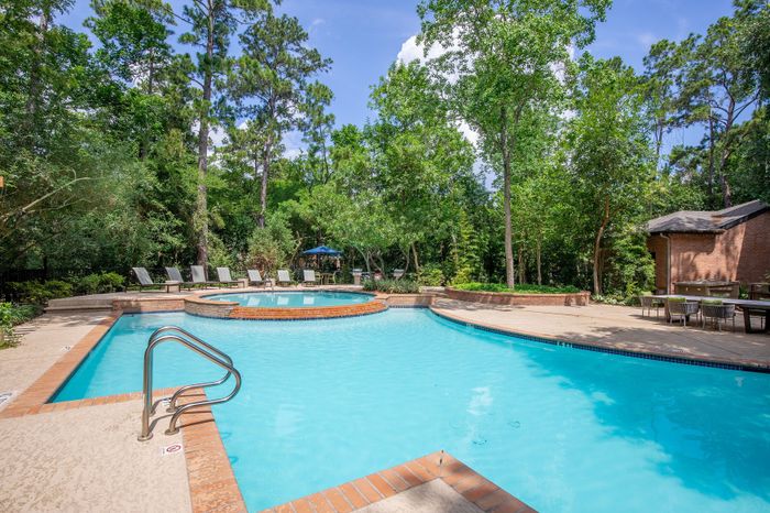 Inviting outdoor swimming pool surrounded by lush greenery and comfortable lounge chairs, perfect for relaxation.