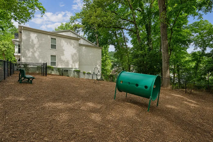 Charming outdoor dog park with playful equipment and lush green trees at Avana Cumberland pet-friendly community.