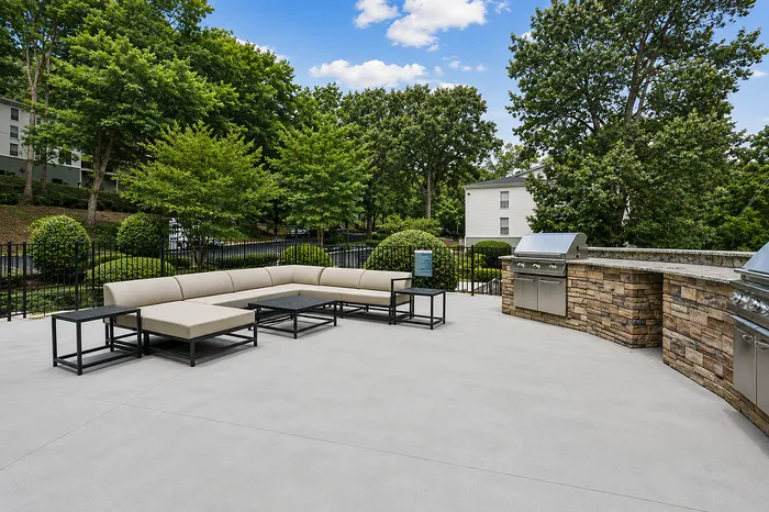 Inviting outdoor patio with modern stone BBQ grills and lush greenery at Avana Cumberland luxury apartment community.