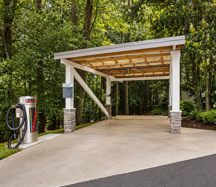 Modern covered car wash area with vacuum cleaner in lush forest setting at Avana Cumberland.