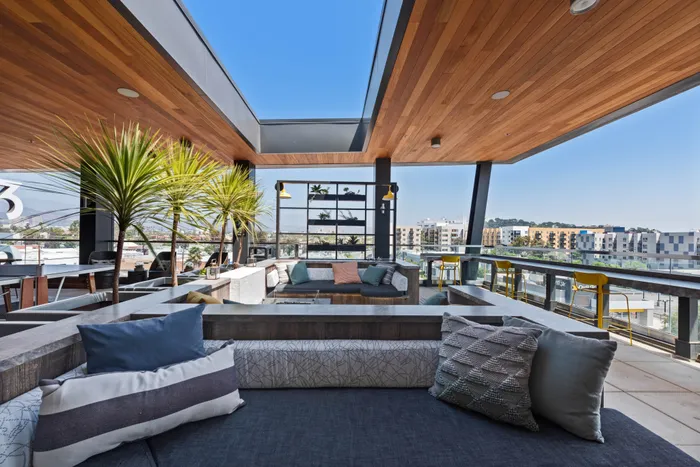 Stunning outdoor rooftop lounge with modern seating, vibrant greenery, and panoramic city views.