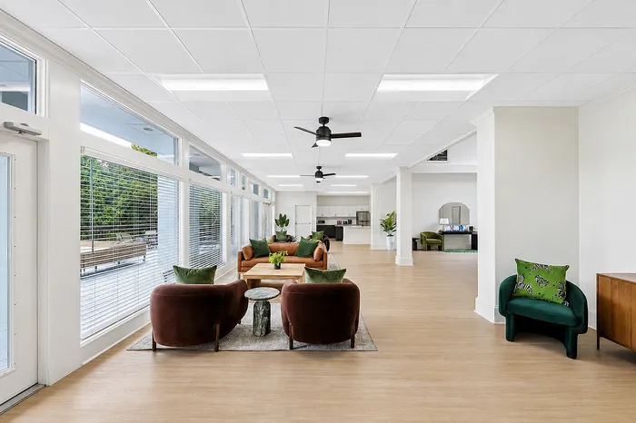 Elegant, spacious living area with floor-to-ceiling windows, stylish seating, and modern decor, offering a bright and inviting atmosphere.