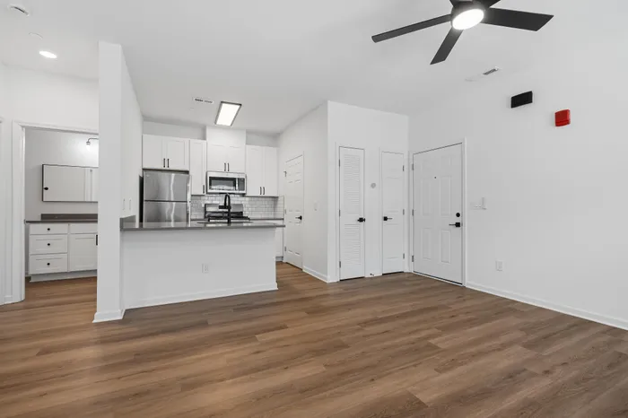 Modern apartment interior featuring sleek kitchen with stainless steel appliances, elegant hardwood flooring, and minimalist design.