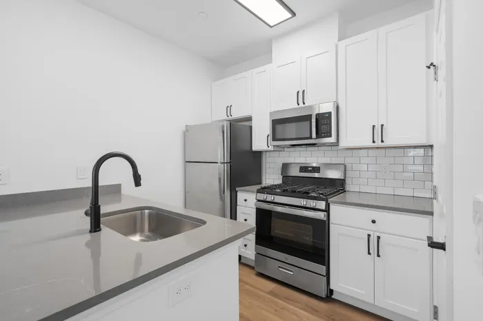 Modern kitchen with sleek white cabinetry, stainless steel appliances, and a chic gray countertop.