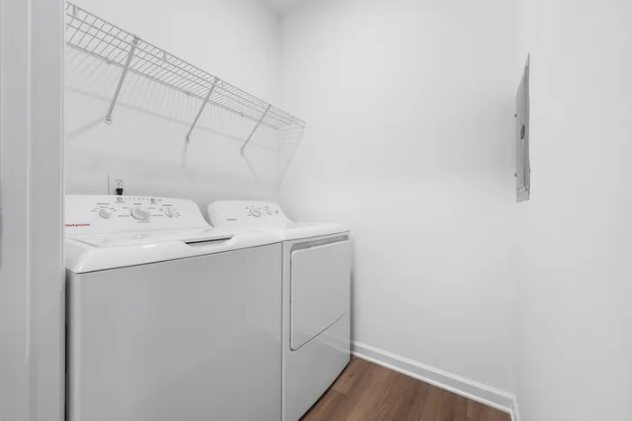 Chic laundry room featuring modern white washer and dryer with sleek shelving in a bright, clean space.