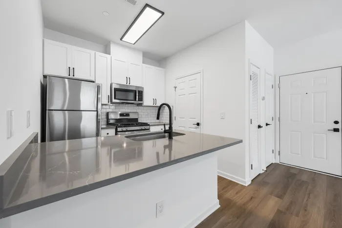 Modern kitchen with sleek stainless steel appliances, elegant white cabinetry, and a stylish gray countertop, offering a chic and functional space.