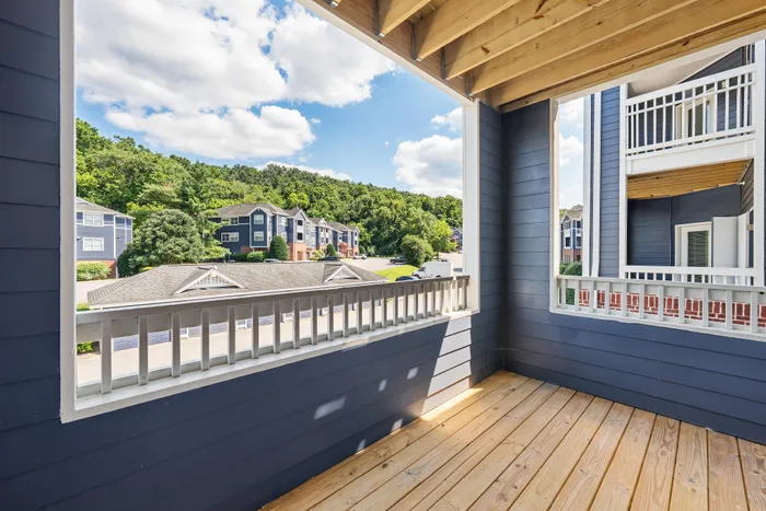 Charming balcony view featuring modern apartments surrounded by lush greenery and a peaceful neighborhood setting.