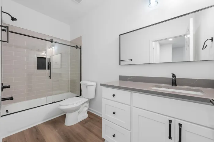 Sleek modern bathroom with a large mirror, elegant glass shower door, and contemporary fixtures.