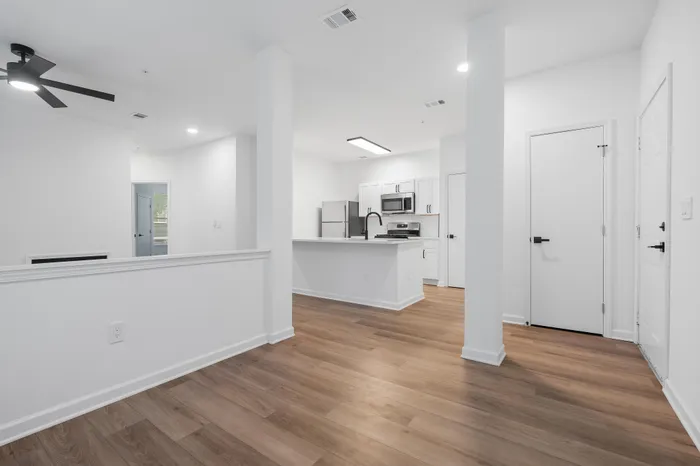 Modern apartment interior with elegant wooden flooring, a sleek kitchen, and bright open spaces for comfortable living.