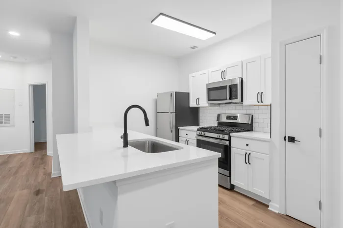 Modern kitchen with sleek black fixtures, stainless steel appliances, and elegant white cabinetry, offering a stylish and functional cooking space.