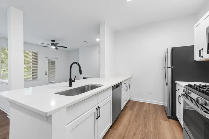 Modern kitchen with elegant white cabinetry, sleek black fixtures, stainless steel appliances, and stylish hardwood floors.