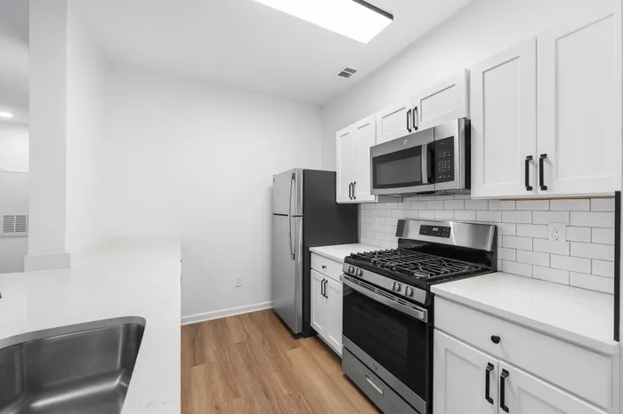 Modern kitchen with sleek stainless steel appliances, fresh white cabinetry, and elegant wood flooring.