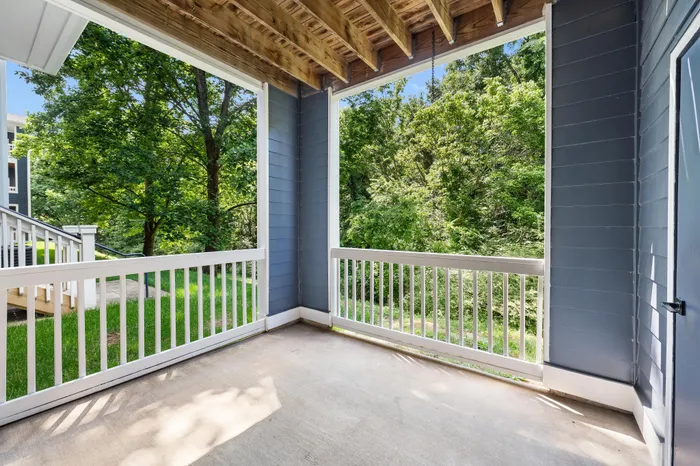 Inviting apartment balcony with white railings, offering scenic views of lush greenery, perfect for relaxation.