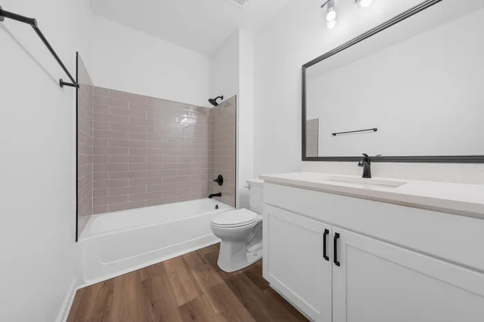 Modern bathroom featuring a sleek bathtub with elegant tile backsplash, pristine white cabinets, and stylish fixtures.