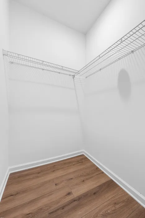 Spacious walk-in closet with elegant hardwood flooring and ample shelving.