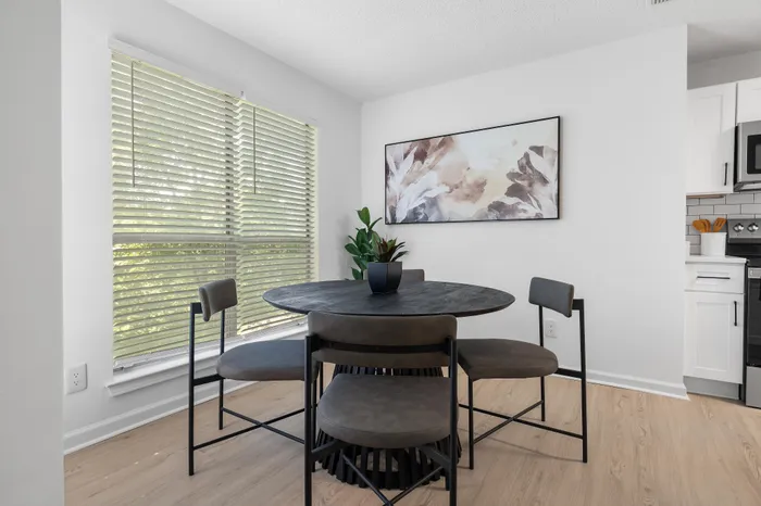 Chic dining area with elegant round table, modern chairs, and natural light filtering through large windows.