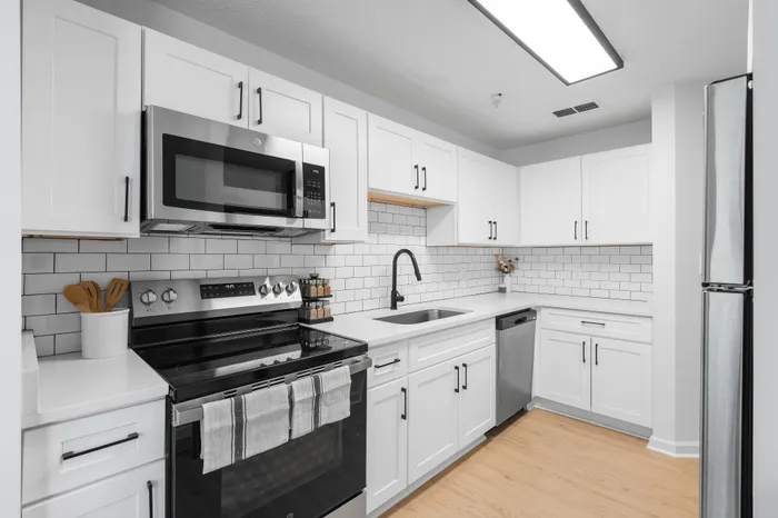 Modern kitchen with sleek white cabinetry, stainless steel appliances, and stylish subway tile backsplash.