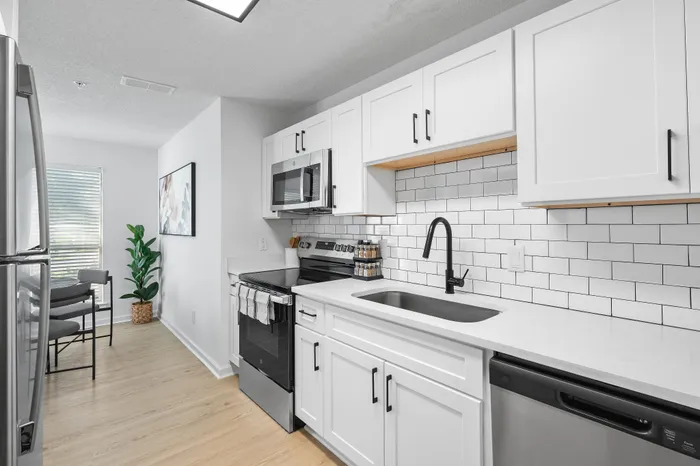 Modern kitchen with sleek white cabinets, stainless steel appliances, and a chic black faucet, offering a bright and inviting space.