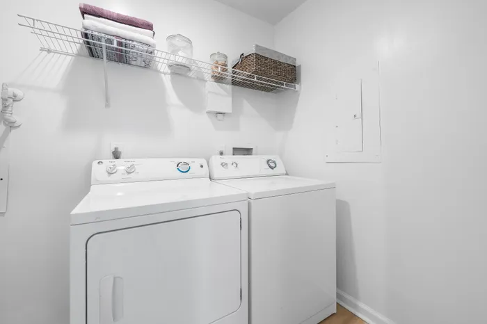 Bright laundry room with modern washer and dryer, featuring organized shelving for efficient storage solutions.