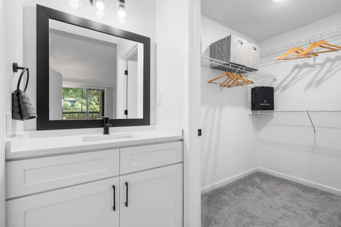 Bright and modern closet space with ample shelving and elegant vanity, offering a refreshing view through a large mirror.