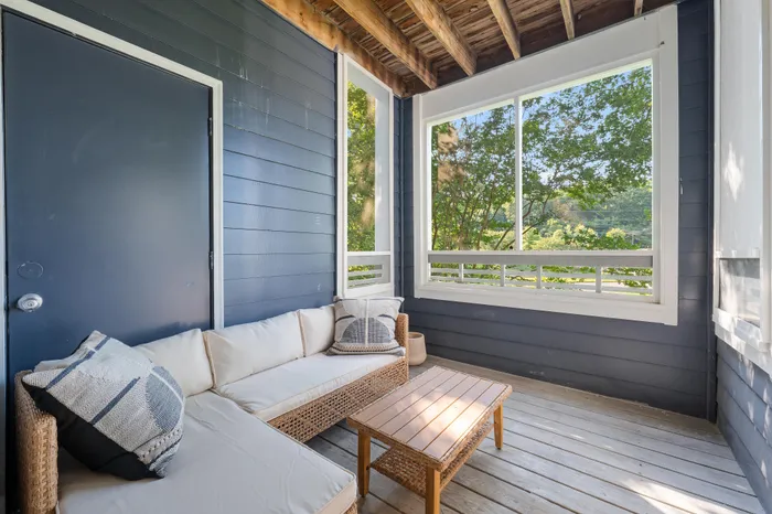 Charming screened porch with cozy wicker seating and lush green views, perfect for relaxation and enjoying the outdoors.