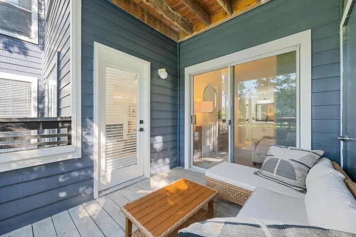 Charming apartment patio with cozy seating and views into a well-lit interior through glass doors.