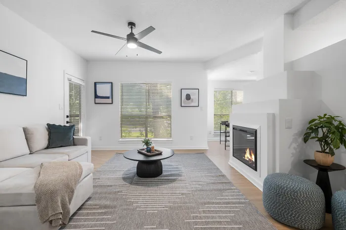 Bright and modern living room with cozy fireplace, sleek ceiling fan, and stylish decor, perfect for relaxation and comfort.