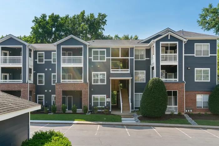 Elegant apartment complex showcasing a modern three-story building with spacious balconies and lush greenery.