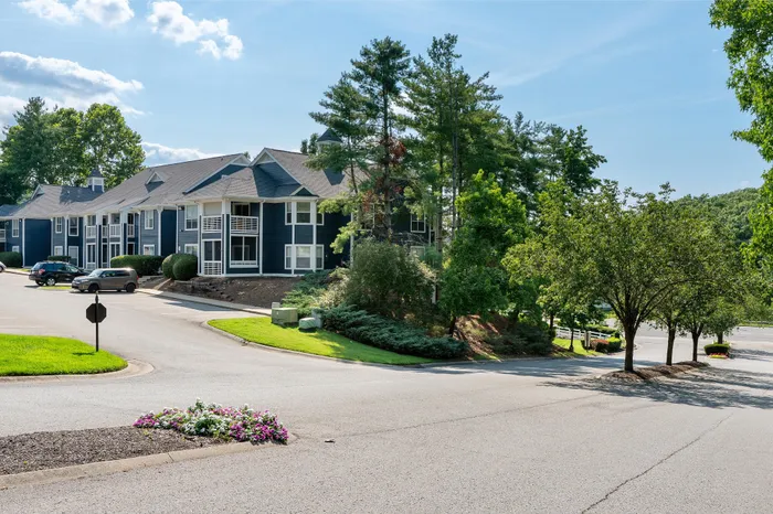 Charming apartment complex nestled amidst lush greenery and vibrant blossoms, featuring spacious balconies and ample parking.