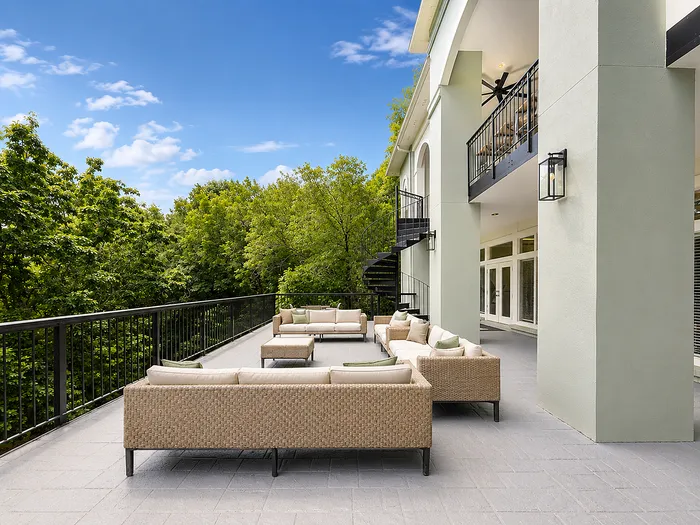 Luxurious outdoor terrace featuring stylish wicker seating, nestled against lush greenery with a serene ambiance.