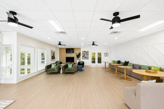 Bright and modern community lounge featuring elegant seating, large windows, and stylish decor with a nature-inspired palette.