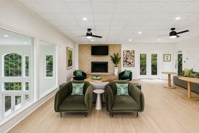 Elegant living room with modern green chairs, large windows, and cozy fireplace, offering a perfect blend of style and comfort.