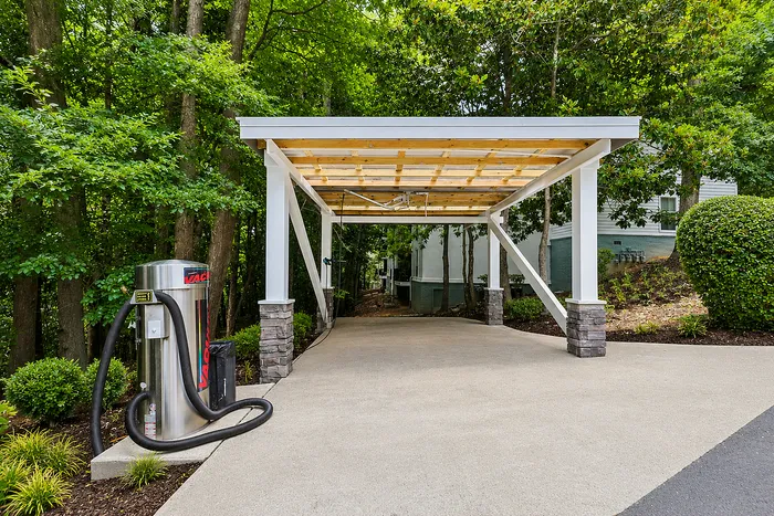 Elegant carport with a modern design set amidst lush greenery, featuring a convenient vacuum station for easy car maintenance.