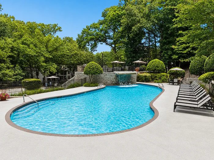Luxurious outdoor pool area with pristine blue water, surrounded by lush greenery and comfortable lounge chairs, ideal for relaxation and leisure.