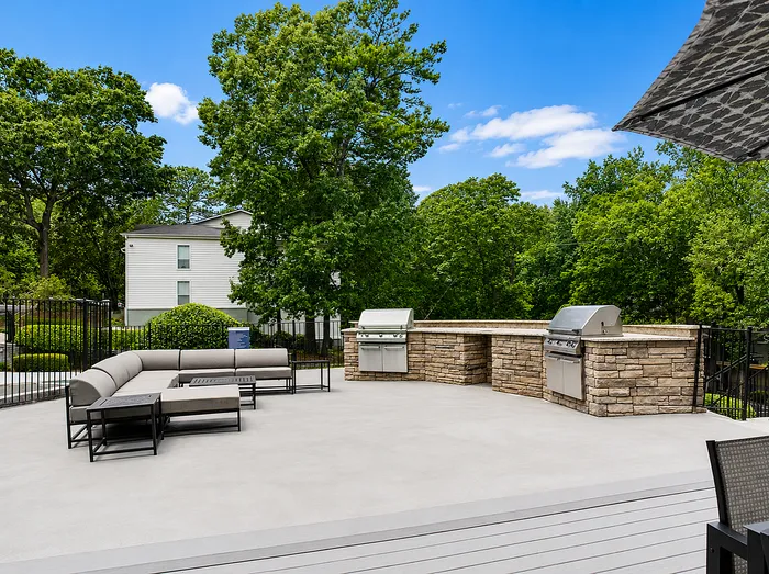 Chic outdoor patio with comfortable seating, modern grill stations, and lush greenery, perfect for entertaining and relaxation.