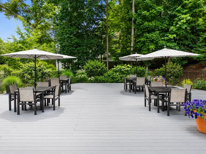 Elegant outdoor patio with stylish tables, cozy umbrellas, and lush green surroundings, perfect for relaxation and gatherings.