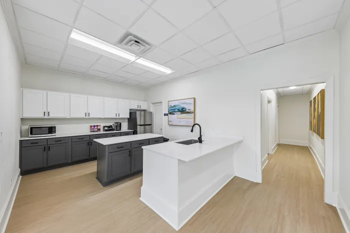 Modern kitchen with sleek cabinetry, spacious countertops, and chic lighting, leading to an inviting hallway with elegant artwork.