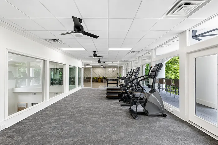 Modern indoor fitness center featuring state-of-the-art exercise equipment, large windows with scenic views, and sleek ceiling fans for a refreshing workout experience.