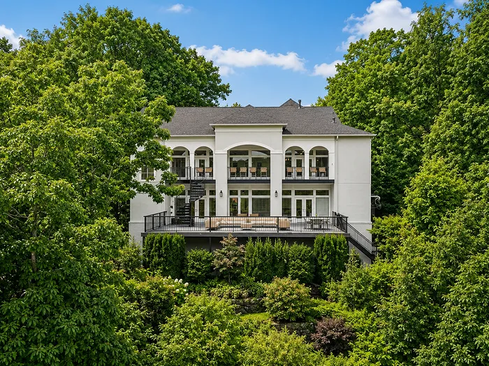Elegant two-story residence surrounded by lush greenery, featuring a spacious balcony and expansive windows for natural light.