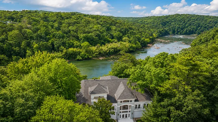 Elegant estate surrounded by lush greenery with a stunning river view, offering a serene and private retreat in nature.
