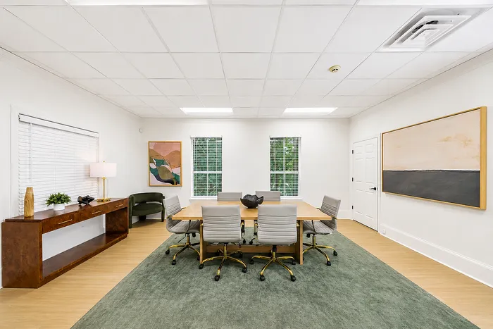 Elegant and spacious office space featuring a stylish conference table with plush chairs, large windows, and tasteful modern decor.