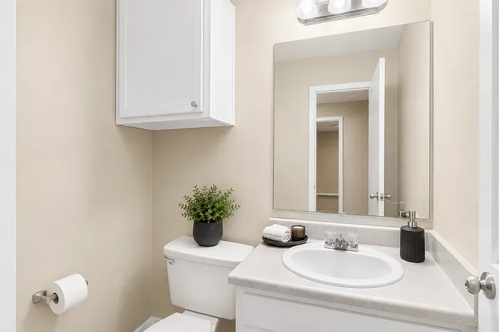 Charming bathroom with elegant fixtures, featuring a sleek sink, large mirror, and lush plant for a serene ambiance.