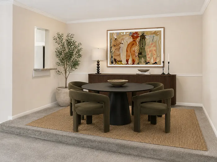 Elegant dining area with a modern round table, plush olive chairs, artistic wall painting, and ambient lighting, offering a cozy yet sophisticated atmosphere.