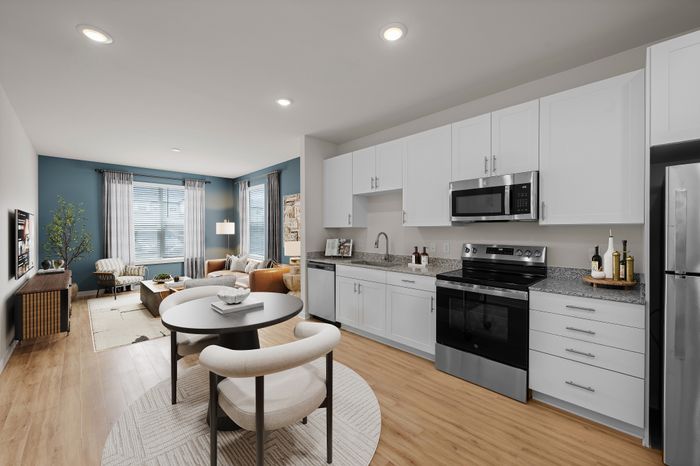 Modern open-plan apartment featuring a sleek kitchen with stainless steel appliances and a cozy living area with abundant natural light.